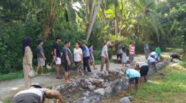 KOMPAK: Mahasiswa KKN Posko 16 dan warga Kalisoka bergotong royong membangun penyangga jalan di lokasi rawan longsor, penuh semangat kebersamaan. (Foto:Kayyis). 