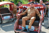 Bupati Sumenep, Achmad Fauzi, mencoba mengendarai becak listrik usai menyerahkan bantuan secara simbolis kepada para abang becak di Pendopo Agung. (Foto:Klik Times). 