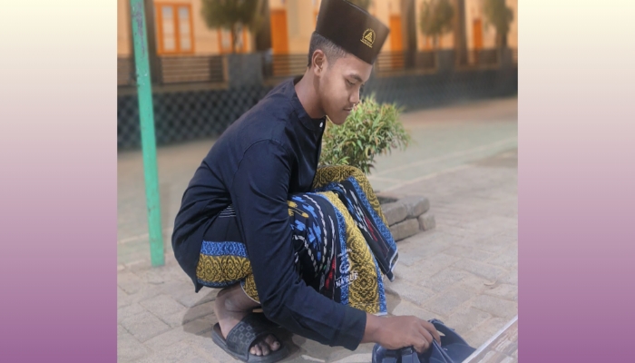 Seorang santri membalikkan sandal milik kiai sebagai bentuk penghormatan dan ngalap barokah di lingkungan pesantren. (Foto:Dit). 