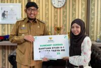 LUAR BIASA: Bupati Achmad Fauzi Wongsojudo menyerahkan secara simbolis bantuan beasiswa kepada mahasiswi asal Sumenep, Nanda Balqis. 