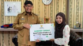 LUAR BIASA: Bupati Achmad Fauzi Wongsojudo menyerahkan secara simbolis bantuan beasiswa kepada mahasiswi asal Sumenep, Nanda Balqis. 