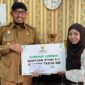 LUAR BIASA: Bupati Achmad Fauzi Wongsojudo menyerahkan secara simbolis bantuan beasiswa kepada mahasiswi asal Sumenep, Nanda Balqis. 